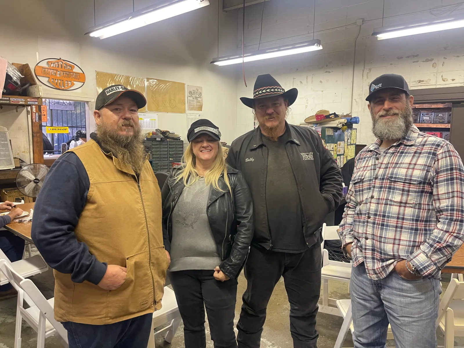Group portrait inside the shop — leather jackets, cowboy hat, ball caps