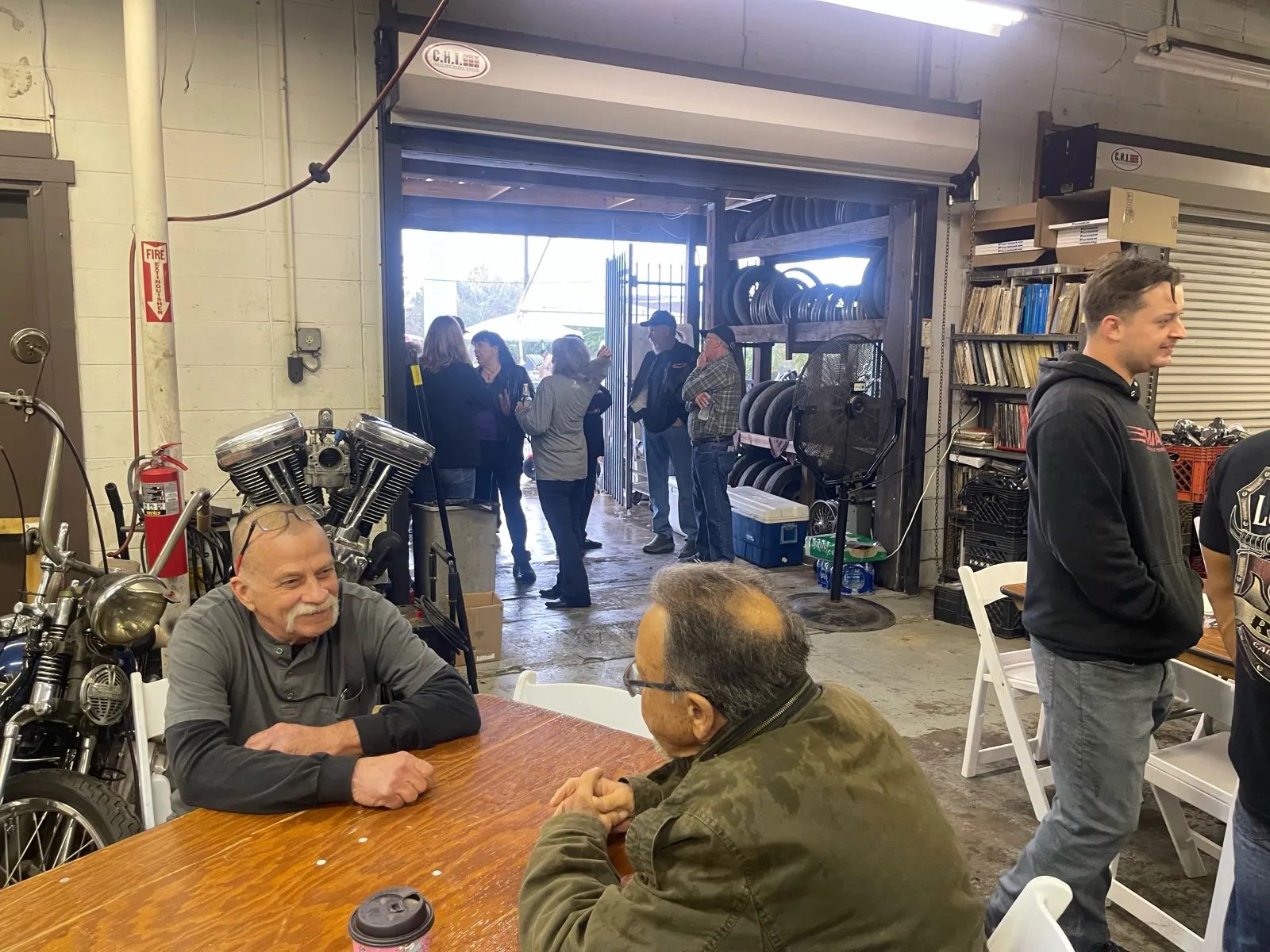 Inside the McCreations shop — vintage Harley engine on the left, group at the tables, library shelves